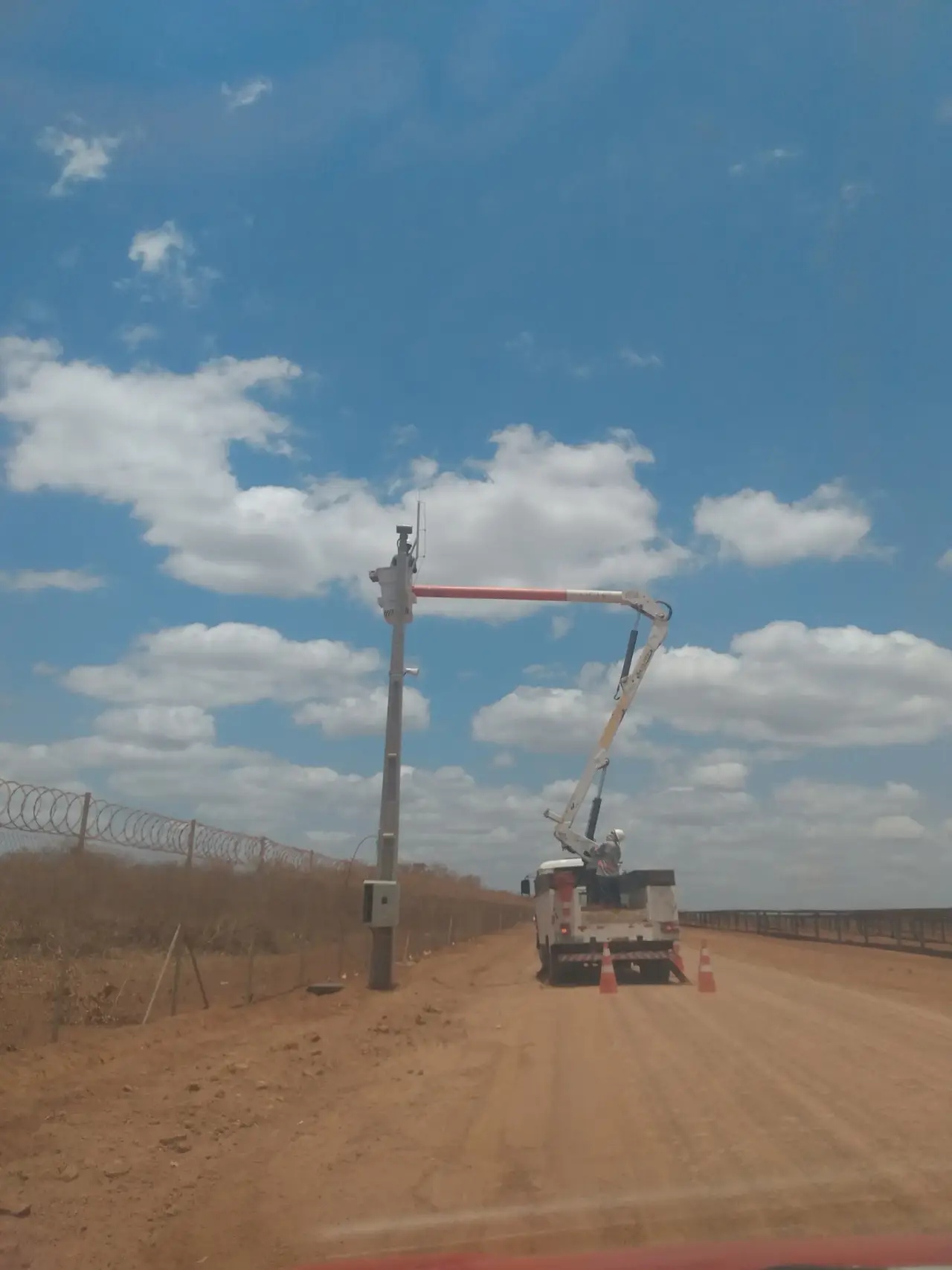 Caminhão munck instalando câmera de segurança em poste